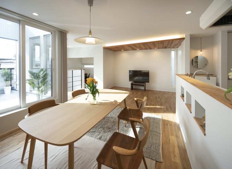 ダイニングの向こうに天井をレッドシダーで貼ったリビングが見える写真