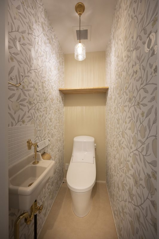 トイレの手前に白い手洗い器がある写真。壁はアクセントウォール。
