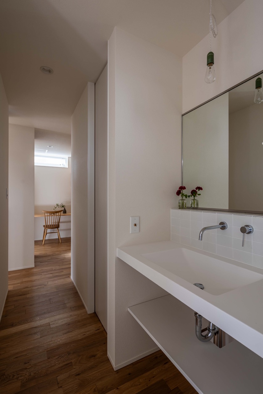 白い洗面カウンターにタイルの立ち上がり。