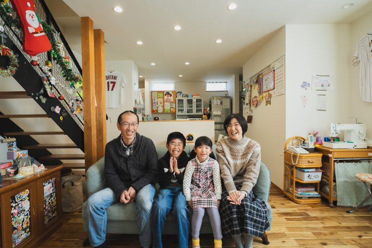 ４人家族がリビングのソファに座っている様子